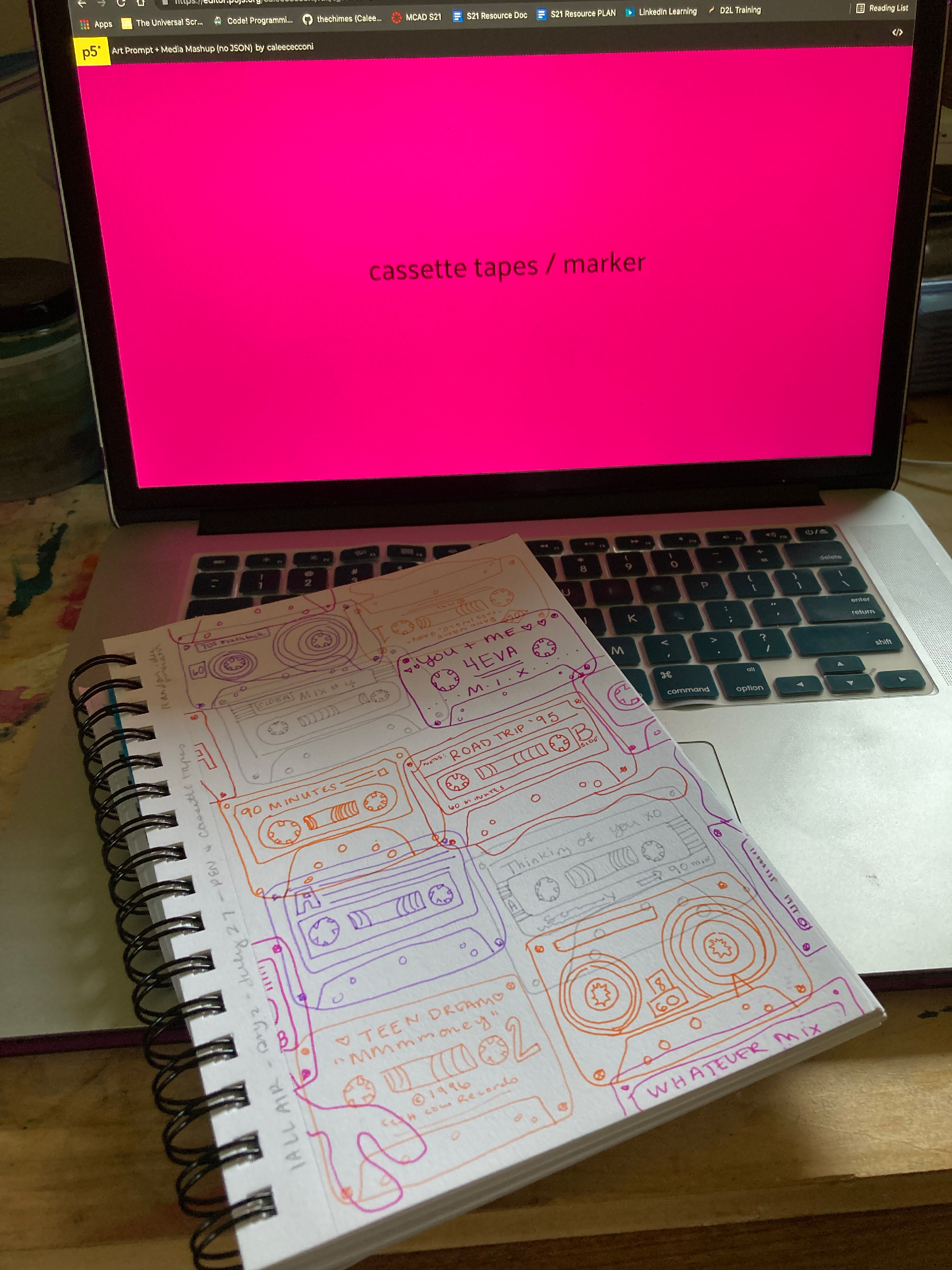 laptop computer with the words "cassette tape" and "marker" with a sketchbook open to a page of cassette tape drawings