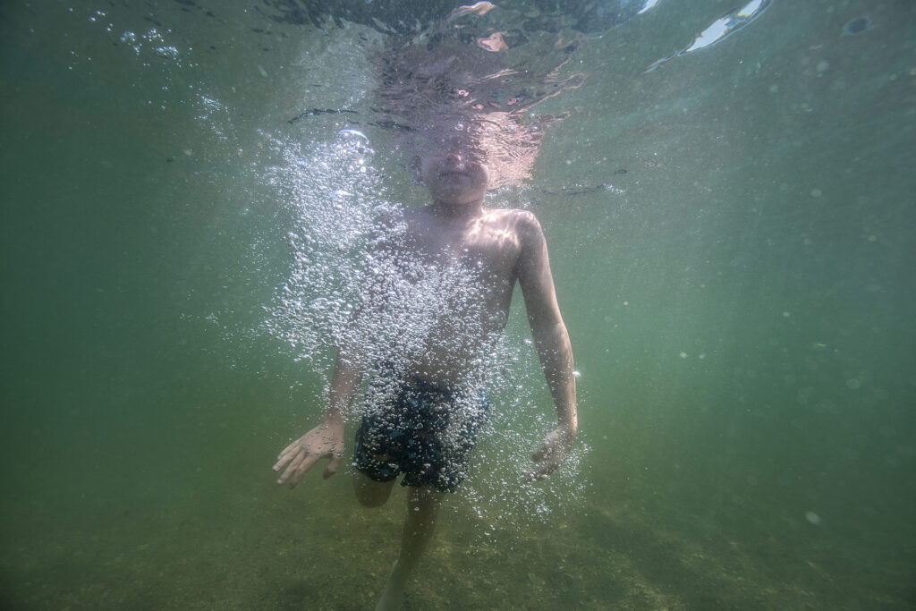 Underwater portrait of a young boy playing in West Lake Okoboji photographed by Isabelle Hayeur